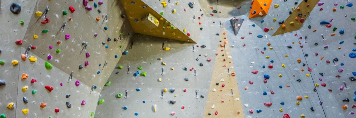 Kletterwand mit bunten Klettergriffen, im Vordergrund stehen zwei blaue Liegestühle